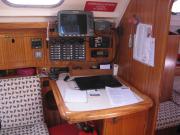 Die Navigationsecke mit dem Kartentisch im Zentrum, darüber das Schaltpanel für die elektrische Anlage des Bootes, darüber wiederum der Radarbildschirm und Seekartenplotter, das Navtexgerät, das UKW-Funkgerät, ein Autoradio zum Musik- und Nachrichtenhören.