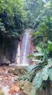 Ein etwa zehn Meter hoher Wasserfall inmitten eines tropischen Waldes.